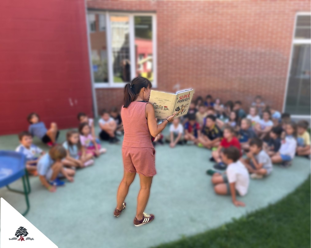 Docente leyendo un cuento sobre la diversidad y los talentos personales a alumnado de Primaria en el patio del Colegio Juan de Lanuza.