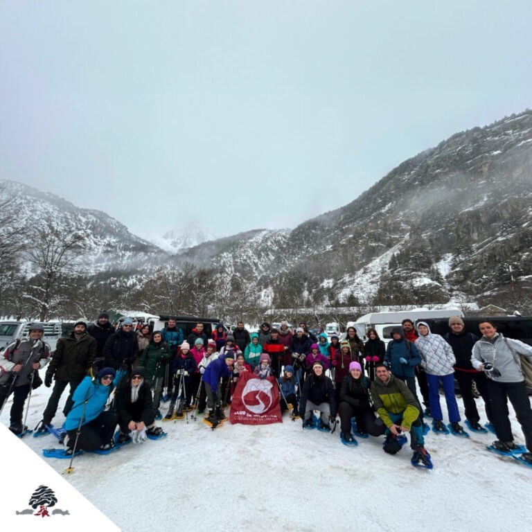 Grupo de alumnos, familias y profesores del Club de Montaña Juan de Lanuza durante la salida con raquetas de nieve en Baños de Panticosa, con paisaje nevado de montaña al fondo.