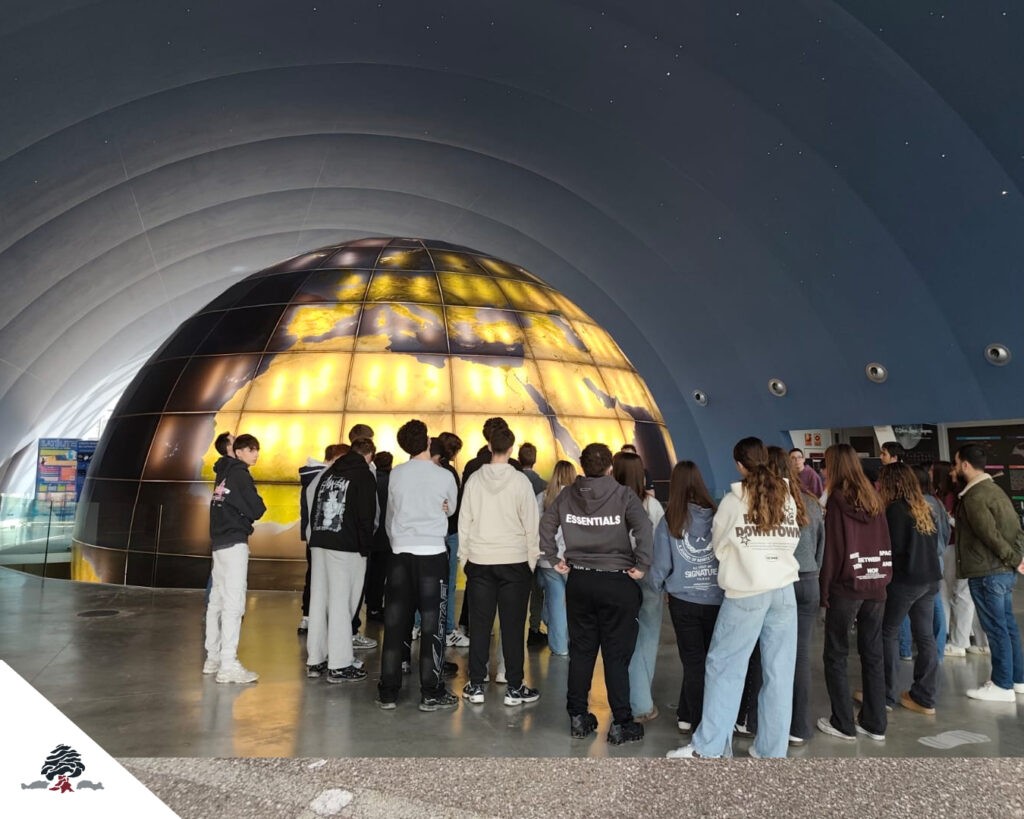 Alumnos de Secundaria del Colegio Juan de Lanuza visitando el Planetario de Huesca, observando una gran esfera terrestre iluminada durante una actividad educativa.