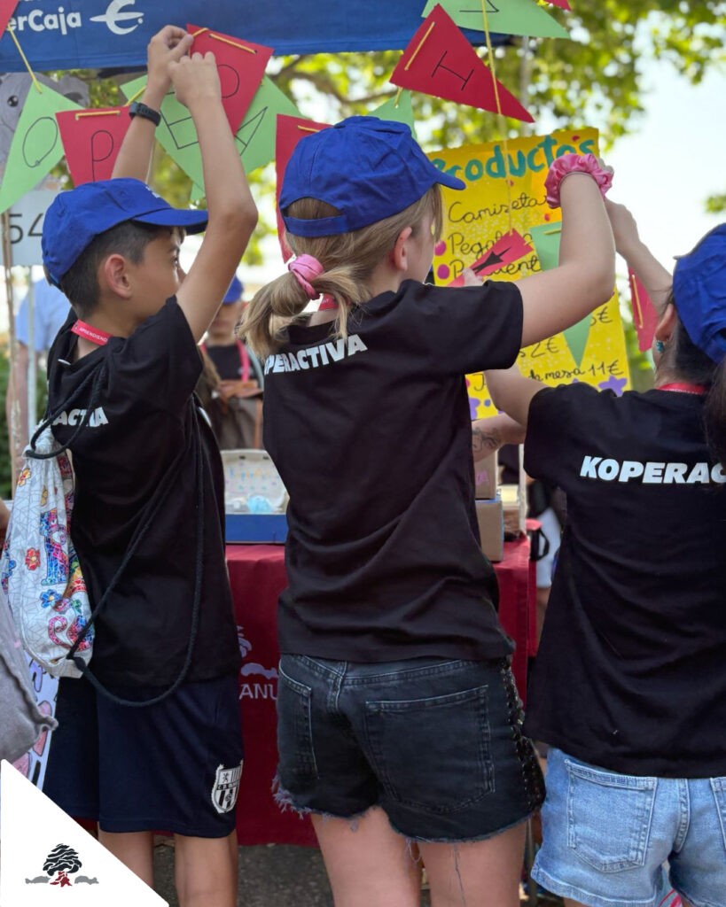 Estudiantes con camisetas de Koperactiva decoran el puesto de su cooperativa escolar.