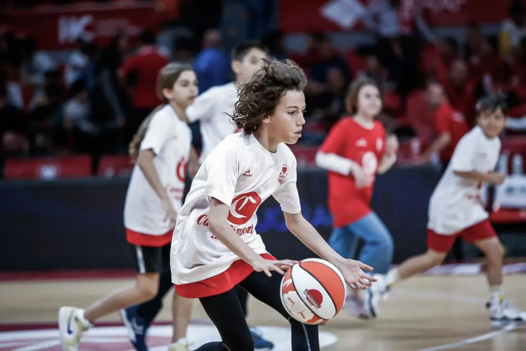 Estudiante practicando baloncesto en una actividad deportiva