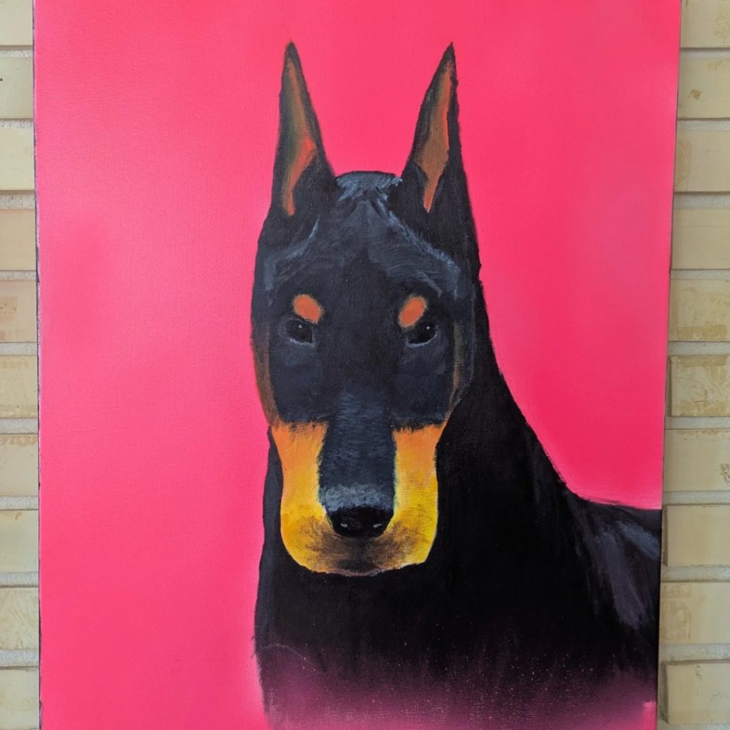 Retrato pintado de un dóberman sobre fondo rosa, obra de alumnado de 4º de ESO