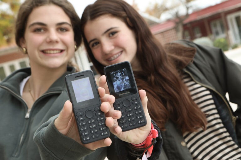 Dos estudiantes muestran los teléfonos móviles básicos del proyecto Más vida, menos redes.