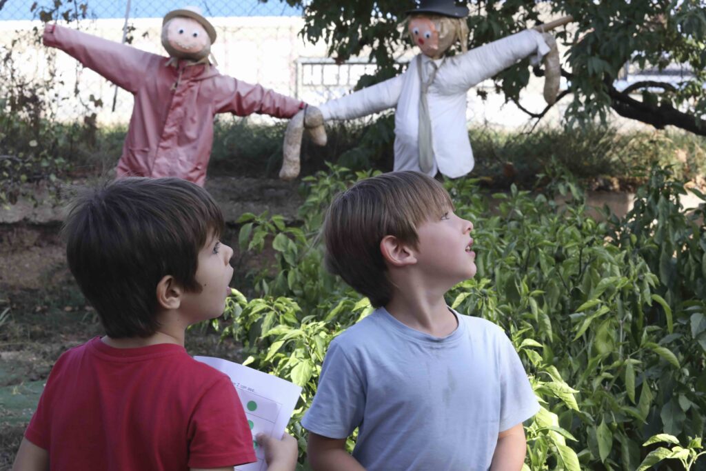 Dos alumnos observan los espantapájaros del huerto escolar del Colegio Juan de Lanuza.
