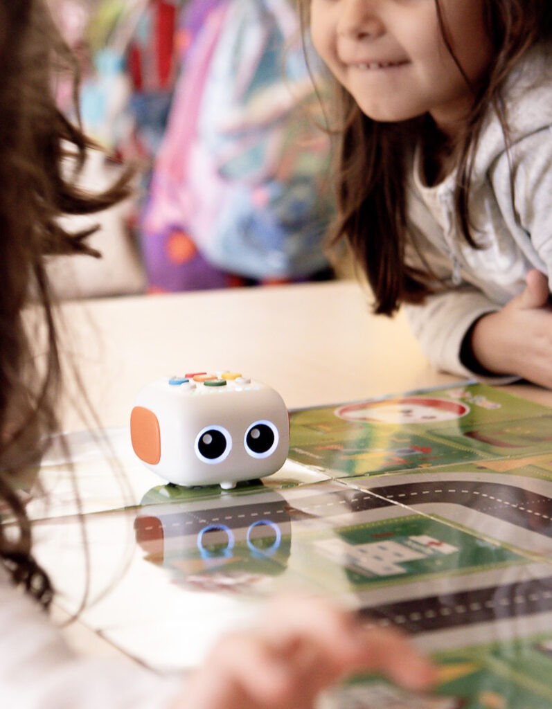 Alumna sonriente durante una actividad de pensamiento computacional con un pequeño robot